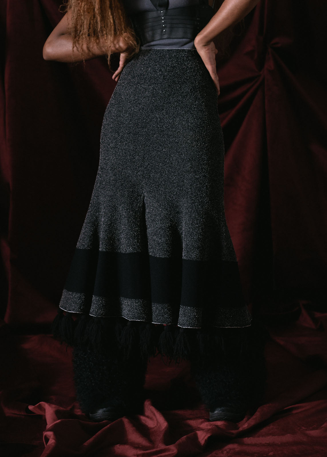 falda gris oscuro corte A larga, con pompones al final , cintura de resorte y cierre, tejida de resorte con licra coleccion otoño invierno 2024